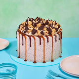 Red Velvet Volcano Cake by Crumbs & Doilies with Oreo crumb icing, cookie dough chunks, and caramel chocolate drip.